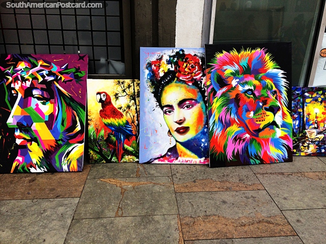 Jesus, a macaw, a lady and a lion, brightly colored paintings for sale on the street in Bogota. (640x480px). Colombia, South America.