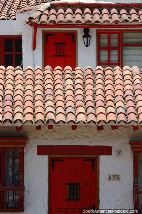 Hermosa fachada de una casa colonial con techo de tejas rojas y puertas rojas en Pueblito Boyacense, Duitama. (480x720px). Colombia, Sudamerica.