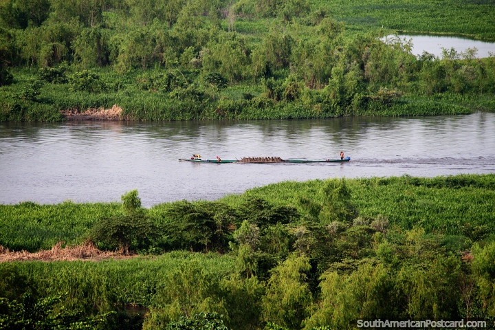 O barco de rio carrega areia ao longo do rio Magdalena em Barrancabermeja, margens verdes exuberantes. (720x480px). Colômbia, América do Sul.