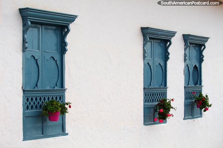3 blue wooden window shutters with pink flower pots and flowers, great style in Barichara. (720x480px). Colombia, South America.