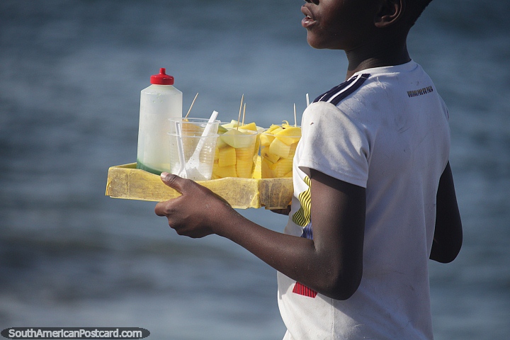 Boy sells cups full of mango pieces on Morro beach in Tumaco. (720x480px). Colombia, South America.