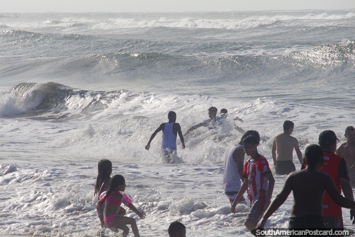Waves come crashing in and the people enjoy cooling off in the tropical climate in Tumaco. (720x480px). Colombia, South America.