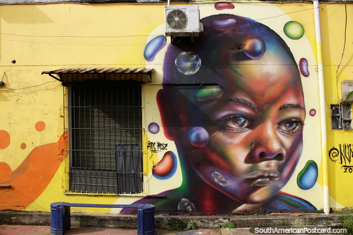 Girl surrounded by jelly beans on a bright yellow wall, street art in Quibdo. (720x480px). Colombia, South America.
