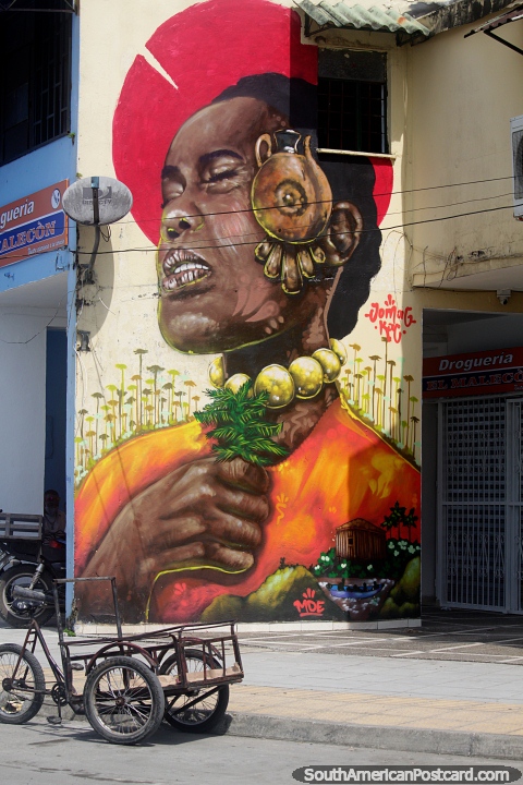 Mural de rua brilhante de uma mulher com um grande brinco e contas segurando folhas, Quibdo. (480x720px). Colmbia, Amrica do Sul.