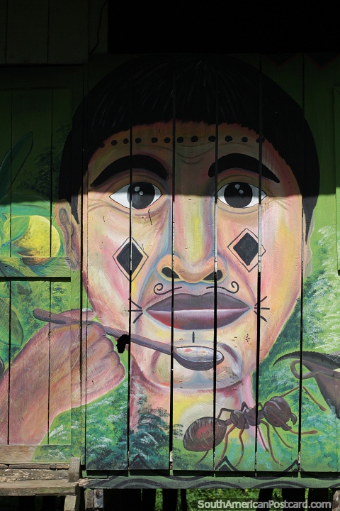 Hombre indígena con una cuchara, una hormiga debajo, mural en el costado de una casa en Mocagua, cerca de Leticia. (480x720px). Colombia, Sudamerica.