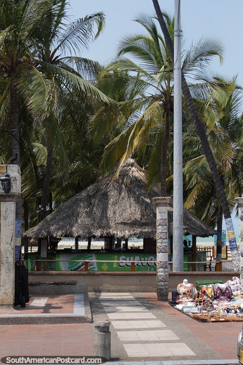 Beach restaurant with thatched roof under palm trees in Riohacha. (480x720px). Colombia, South America.