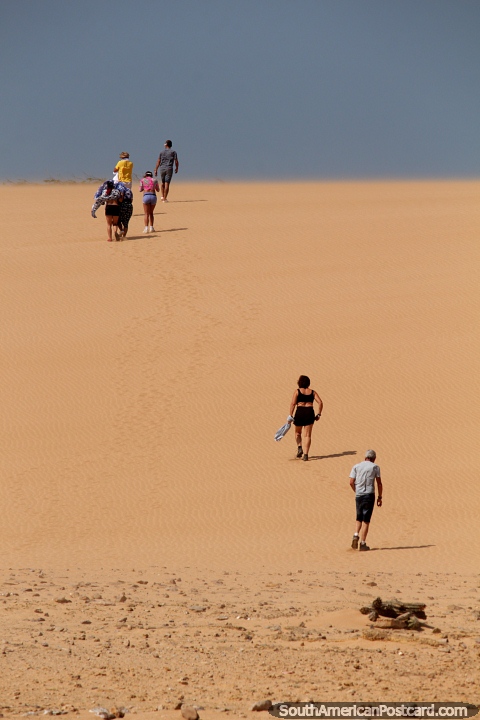 People walk up the sand dunes in Taroa, east of Punta Gallinas. (480x720px). Colombia, South America.
