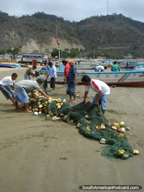Pescadores em Porto Lopez que desemaranha as redes de pesca na praia. (480x640px). Equador, América do Sul.