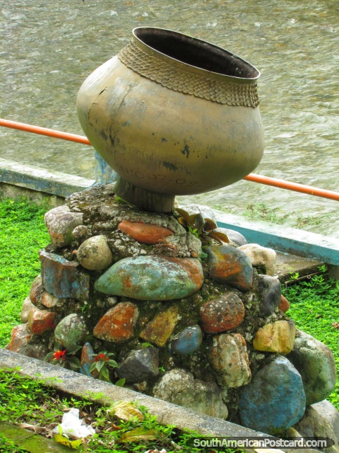 Pote de oro sobre escultura de rocas al lado del río en Tena. (480x640px). Ecuador, Sudamerica.