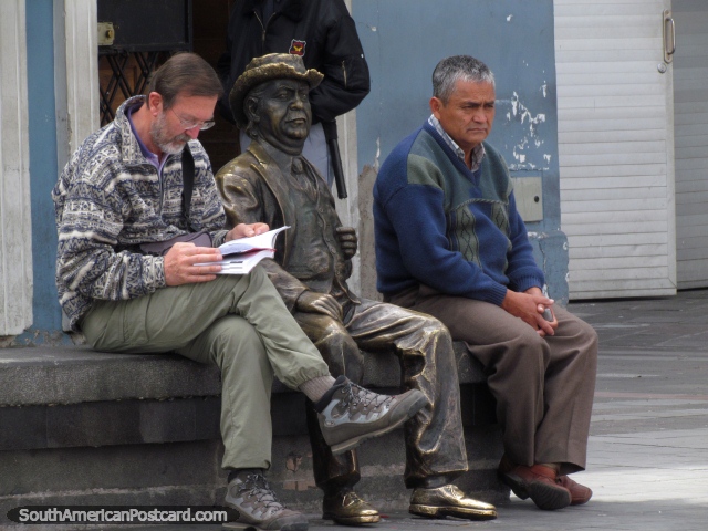 Un hombre de bronce se sienta entre 2 verdaderos hombres en un banco en Quito. (640x480px). Ecuador, Sudamerica.