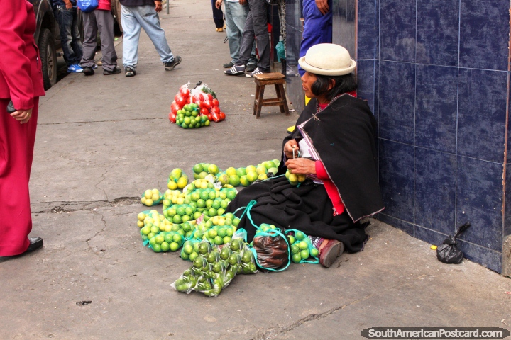 An indigenous woman sells lemons from the sidewalk in Ambato. (720x480px). Ecuador, South America.