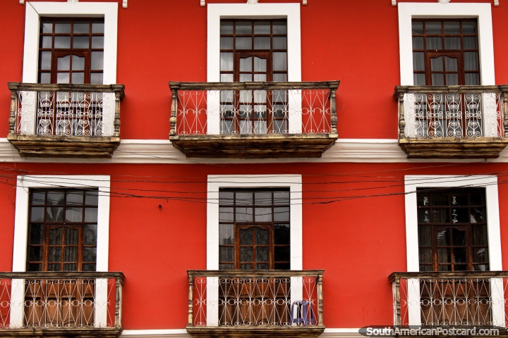 Bien cuidado edificio rojo con balcones de madera y de hierro y ventanas limpias en Guaranda. (720x480px). Ecuador, Sudamerica.