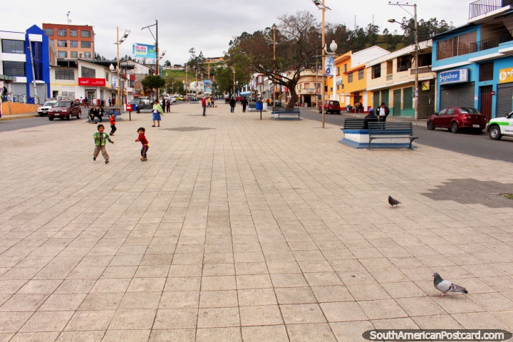 The long plaza in Guaranda, Plaza Roja, kids chase pigeons. (720x480px). Ecuador, South America.