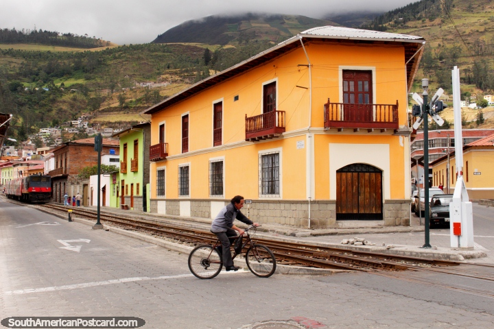 Pistas y edificios y un hombre en una bicicleta, frente a la estación de Alausí. (720x480px). Ecuador, Sudamerica.