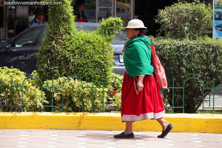 Uma mulher local em passeios verdes e vermelhos ao longo da rua em Alausi. (720x480px). Equador, América do Sul.