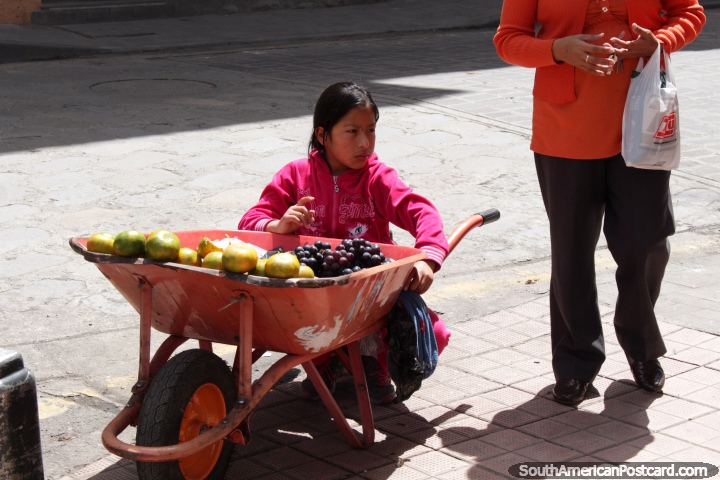 Nia vende uvas y naranjas desde una carretilla en el centro de Cuenca. (720x480px). Ecuador, Sudamerica.