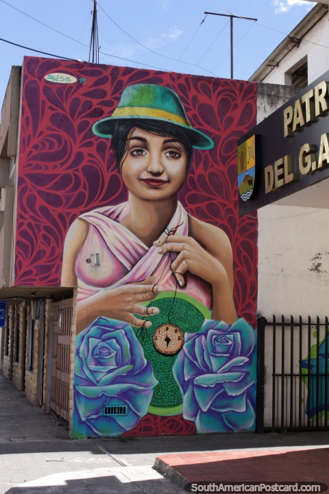 Mujer en un sombrero verde sostiene un colgante, mural en Machachi. (480x720px). Ecuador, Sudamerica.