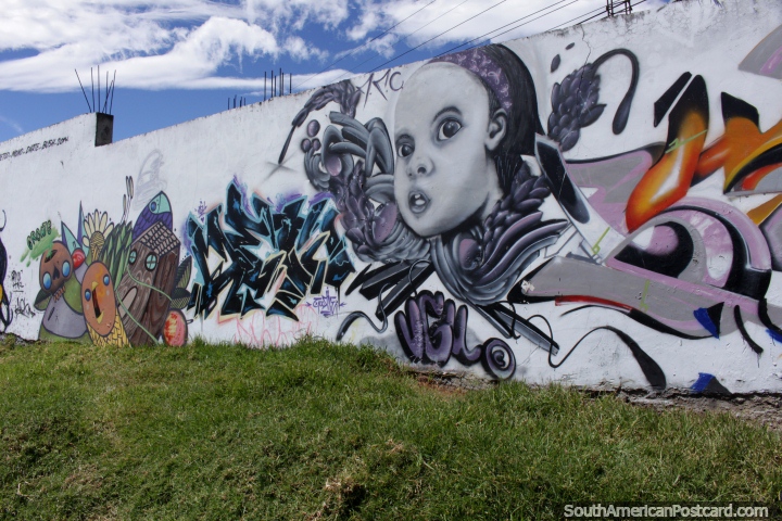 Um childs fica em frente em uma parede de grafite em Machachi. (720x480px). Equador, Amrica do Sul.