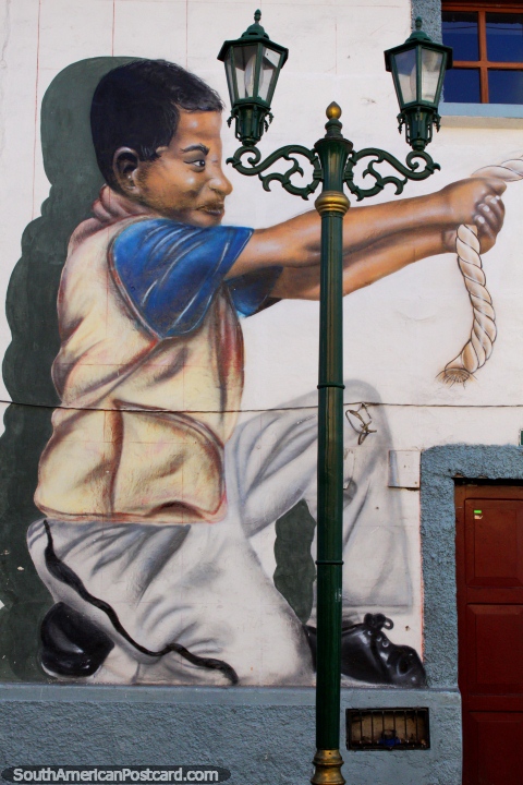 O rapaz puxa uma corda, grande arte de rua em Cayambe. (480x720px). Equador, América do Sul.