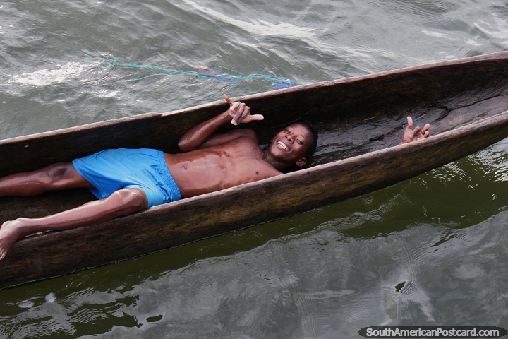 Young man laying back in a wooden canoe, having fun at the port in San Lorenzo. (720x480px). Ecuador, South America.