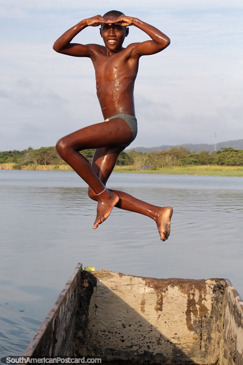 Grande pose aérea, rapaz que salta de uma canoa na água no Rio Esmeraldas. (480x720px). Equador, América do Sul.