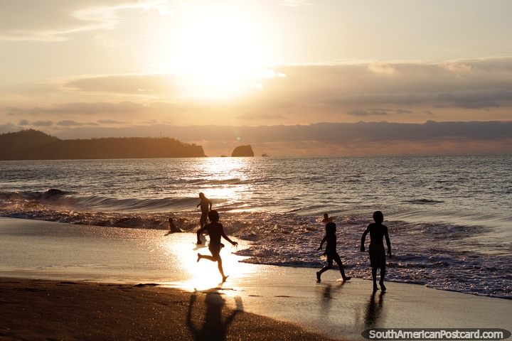 As crianças jogam no ocaso em praia de Atacames, Ilha de Pássaro na distância. (720x480px). Equador, América do Sul.