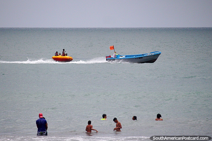 Crianças que montam em volta em um barco inflável que se reboca, divertimento em praia de Atacames. (720x480px). Equador, América do Sul.