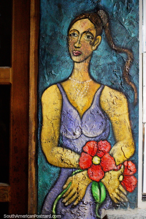 Woman in a purple dress holding red flowers, mural in Montanita, who is she waiting for. (480x720px). Ecuador, South America.
