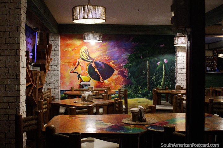 Painting of a beach girl carrying a surfboard while riding a bike inside a restaurant in Montanita. (720x480px). Ecuador, South America.