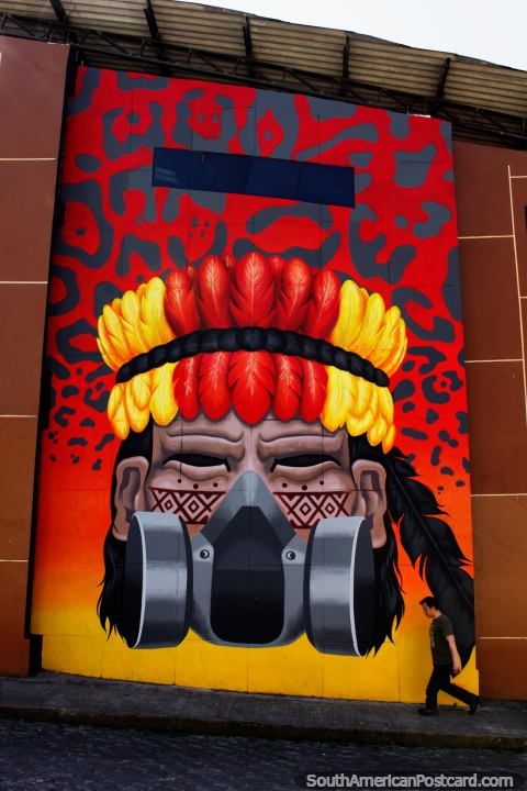 Indio indígena con plumas amarillas y rojas con máscara facial, enorme mural en Zamora. (480x720px). Ecuador, Sudamerica.