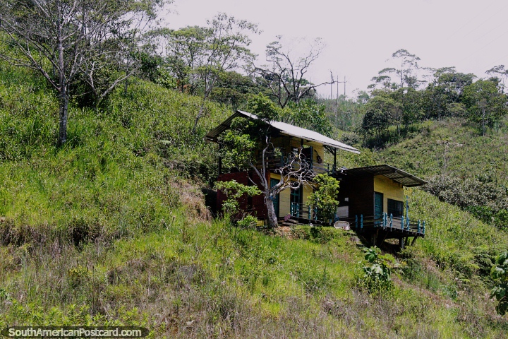As pequenas casas de madeira empoleiraram-se em uma ladeira, violão na parede dianteira, em volta de San Juan Bosco, ao sul de Limon. (720x480px). Equador, América do Sul.