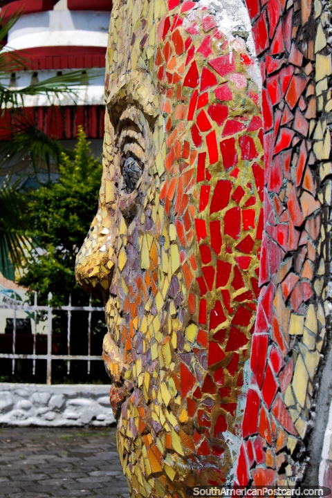 Obra de arte coberta com telhas vermelha e amarela do sol com uma cara em Macas. (480x720px). Equador, América do Sul.