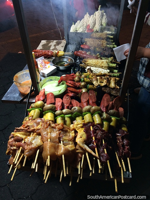 Brochetas de barbacoa con pollo, carne, salchichas y papas, comida callejera en Latacunga por la noche. (480x640px). Ecuador, Sudamerica.