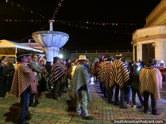 Encontrando-se de pessoas locais em Latacunga a noite, homens que usam xales tradicionais e chapéus. (640x480px). Equador, América do Sul.