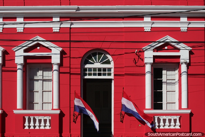 Edificio rojo y blanco con entrada arqueada, ventanas y balcones en Villarrica. (720x480px). Paraguay, Sudamerica.