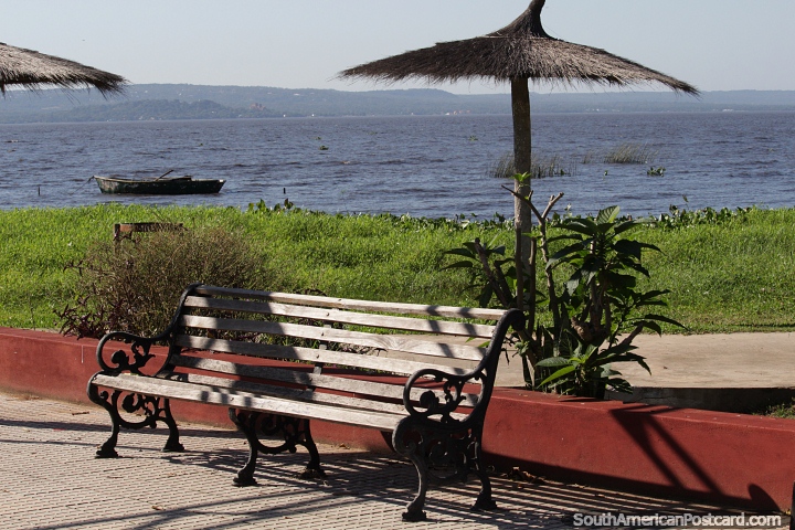 Grassy area with thatched umbrellas and seating beside Lake Ypacarai in Aregua. (720x480px). Paraguay, South America.