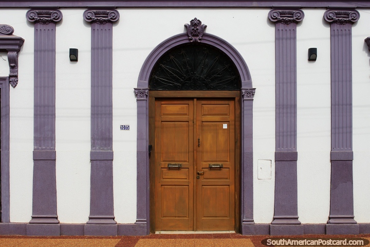 Decorated building facade with ceramic columns and arched wooden door in Concepcion. (720x480px). Paraguay, South America.