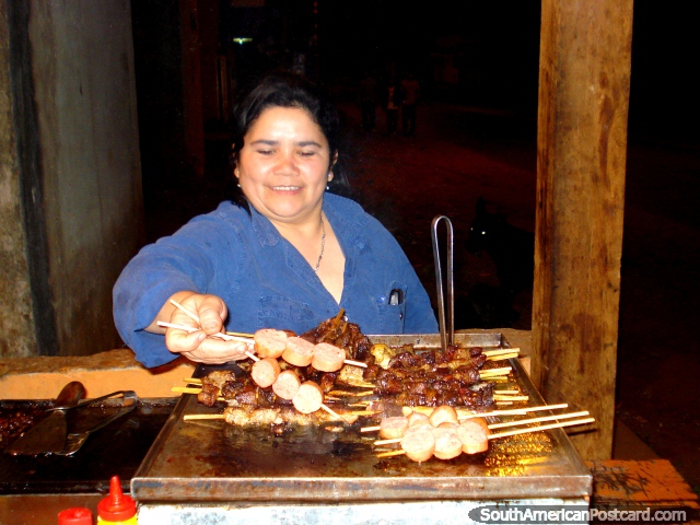 Una señora que prepara filete agradable y kebabs de la salchicha en Ybycui. (640x480px). Paraguay, Sudamerica.