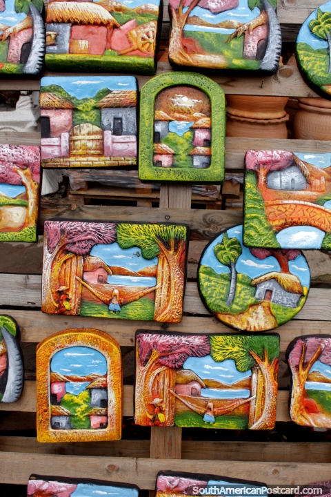 A colorful array of wall plaques depicting beautiful country life scenes, ceramics from Aregua. (480x720px). Paraguay, South America.