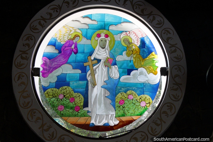 A mulher mantém uma cruz e um livro, os anjos voam a janela de vidro de cima, manchada na Catedral San Blas em Cidade do Este. (720x480px). Paraguai, América do Sul.