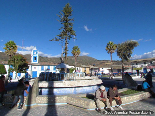 Locals of Celendin enjoy the park, beside fountain, clock tower behind. (640x480px). Peru, South America.