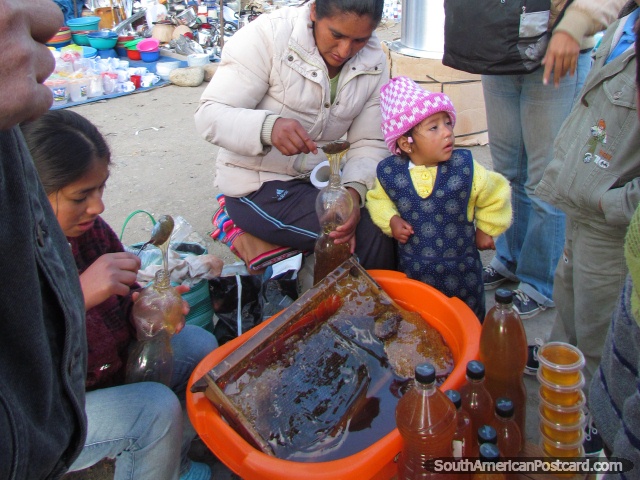 Locals putting fresh honey into bottles at Andahuaylas markets. (640x480px). Peru, South America.