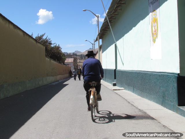 El hombre monta una bicicleta abajo la calle en Yunguyo. (640x480px). Per, Sudamerica.