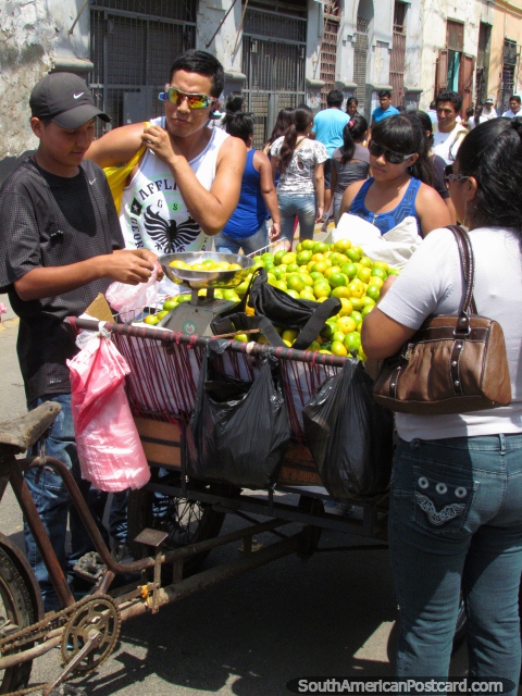 O homem vende mandarins de uma carreta de bicicleta em Lima. (480x640px). Peru, América do Sul.