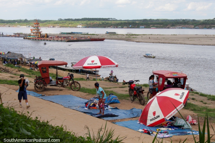 Setting up riverside stalls as a tugboat comes down river in Pucallpa. (720x480px). Peru, South America.