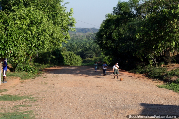 Children walk up an Amazon road with a soccer ball, between Pucallpa and Aguaytia. (720x480px). Peru, South America.
