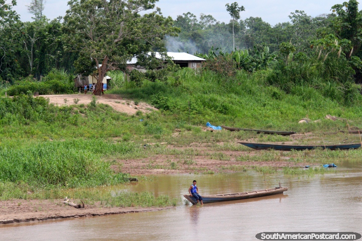 Um homem senta-se na borda da sua canoa e olha o barco a Iquitos passar, o Distrito de Santa Cruz. (720x480px). Peru, Amrica do Sul.