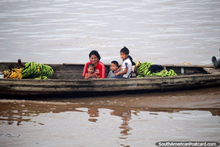 Family on a wooden river canoe with bananas to sell or eat themselves, the Amazon. (720x480px). Peru, South America.