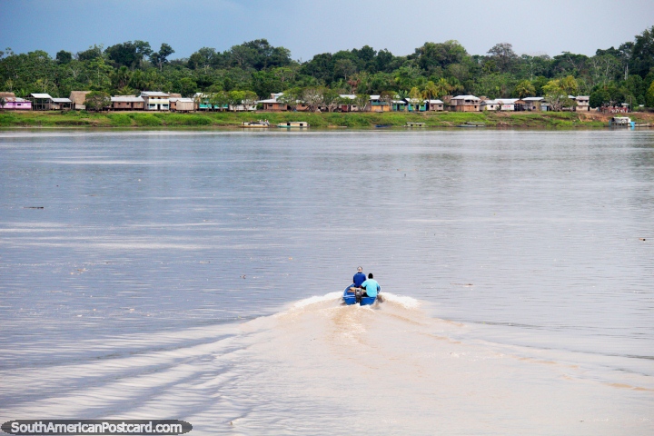A boat goes from our ferry to the river banks to pick people up to bring back and continue the journey east to Nauta. (720x480px). Peru, South America.