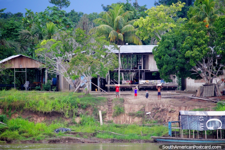 A family waves to the ferry passing by to indicate cargo or passengers need to be brought out, the Amazon, west of Nauta. (720x480px). Peru, South America.